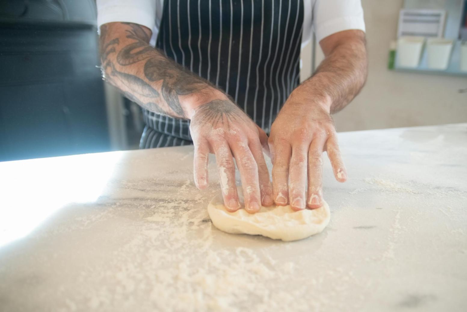 Professional chef demonstrating traditional Italian dough preparation techniques in commercial kitchen training environment